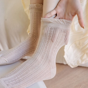 Close-up of beige mesh crew socks with diamond hollow patterns and ruffled lace cuffs