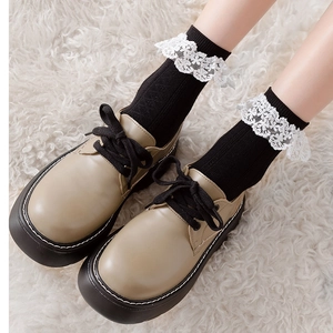 Détail de chaussures plateforme kaki avec chaussettes noires et bordure en dentelle blanche