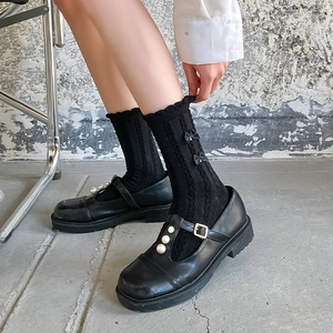 Détail de chaussettes noires JK avec bords à volants et petits nœuds sur modèle