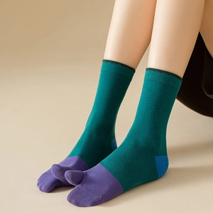 Detail of split-toe socks in dark green and purple color-block with black stripe cuff