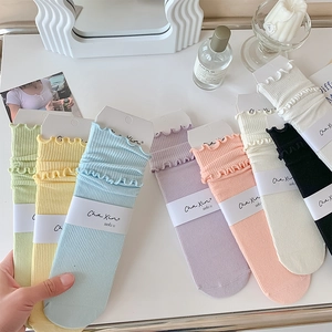 Detail of ruffled trim cotton socks in a variety of pastel colors neatly arranged on a desk