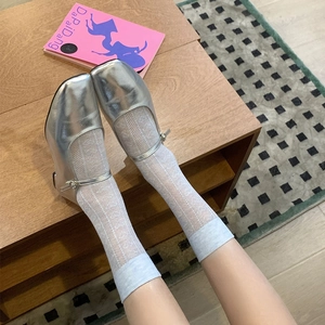 Close-up of silver Mary Jane shoes with heart pattern mesh socks and buckle strap