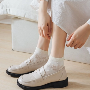 Off-white women's leather loafers paired with floral lace socks on wooden floor