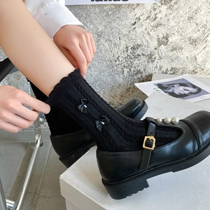 Détails des chaussettes noires côtelées avec nœuds en satin et perles élégantes