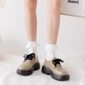 Détail de chaussettes blanches à bordure en dentelle avec chaussures Oxford beiges