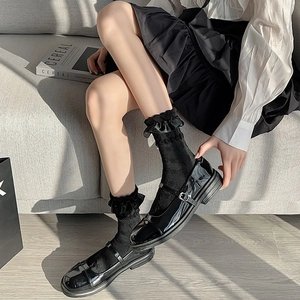 Classic black patent leather Mary Janes with lace socks shown on a wooden floor