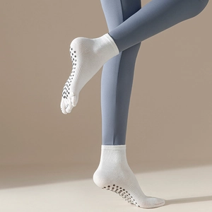 Close-up of white five-toe yoga socks featuring black non-slip silicone grip dots