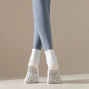 Detail view of anti-slip silicone grip pattern on white yoga crew socks for women