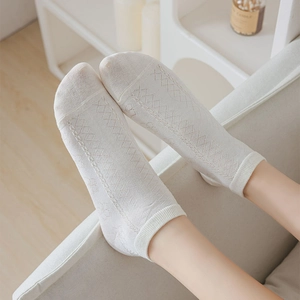 Detail showing white cotton knit socks with diamond pattern and ribbed cuffs on model