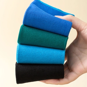 Close-up of four pairs of ribbed Tabi socks in blue green and black stacked neatly