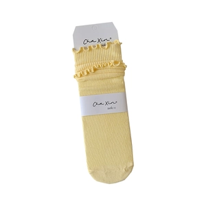 Light yellow ribbed socks with double-layered ruffled edges and classic brand packaging