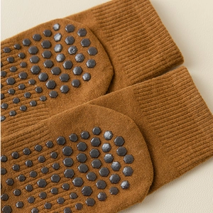 Close-up of brown yoga socks featuring non-slip grey hexagonal silicone grips on the sole