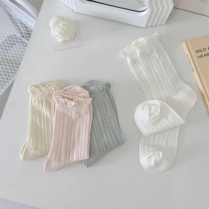 Macro detail of breathable hollow knit white socks with delicate ruffled lace cuffs