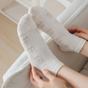 Detailed view of white cotton socks featuring delicate hollow floral knit patterns