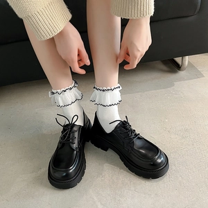Close-up of white lace frill socks styled with black platform oxford shoes for JK look
