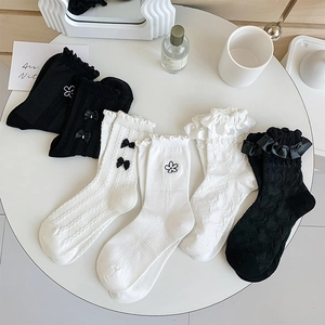 Détails de bords à volants et de nœuds sur des chaussettes en coton blanc et noir