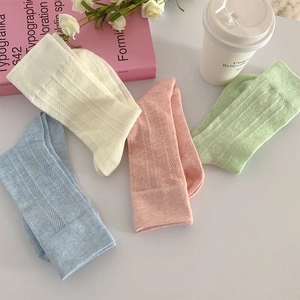 Close-up of four pastel Lolita socks with heart mesh hollow stripes on white desk