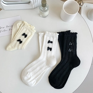 Détail de chaussettes en maille torsadée avec bords à volants et petits nœuds