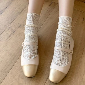 Detail of mesh lace socks paired with almond Mary Jane shoes on a wood floor