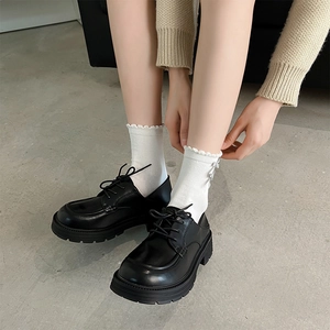 Detail of white ruffle lace socks paired with black matte platform oxford shoes