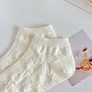 Detailed macro view of white cotton low-cut socks with floral butterfly jacquard texture