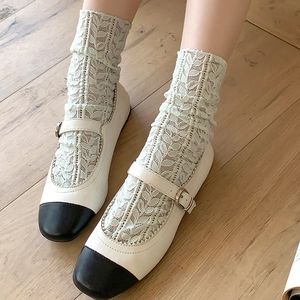 Detail of Mary Jane flats with white lace socks on wooden floor for a vintage look