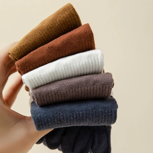 Close-up of five pairs of rib-knit yoga socks in earthy colors held by hand