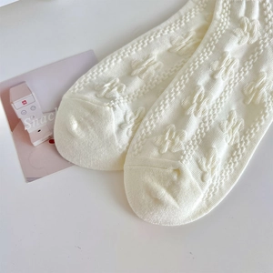 Close-up of white knit low-cut socks featuring sweet 3D animal pattern and cable knit details