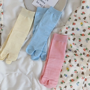 Close-up of three pairs of ribbed cotton two-toe socks in pastel yellow, blue and pink