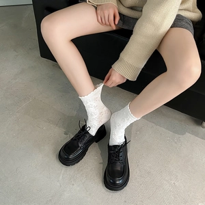 Detail of white floral lace mid-calf socks with black platform loafers in a vintage style