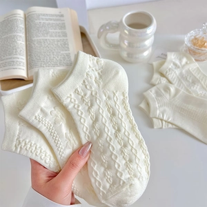 Detail of white cable knit ankle socks showing wave pattern texture and soft cotton fabric