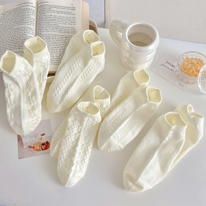 Close-up of assorted off-white cotton socks featuring cable knit and heart patterns