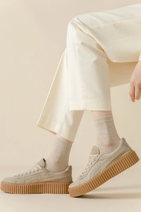Gros plan de baskets compensées en daim beige avec semelle en gomme marron et chaussettes