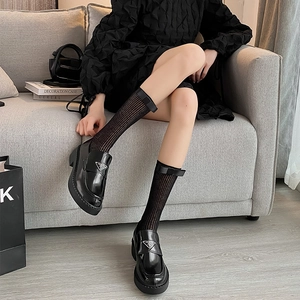 Détail de mocassins à plateforme en cuir noir avec logo métal et chaussettes rayées