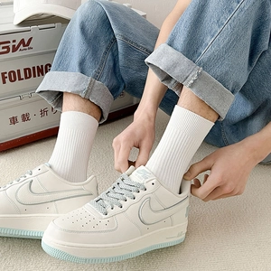 White leather sneakers with light blue logo paired with minimalist white crew socks
