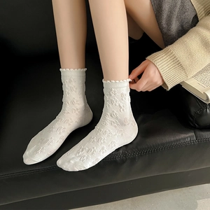 Japanese style white lace socks with floral jacquard and ruffled trim on black sofa