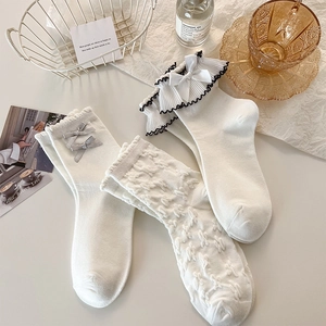 Detail of cream white lace socks with bows and frills on a cozy flat lay setting