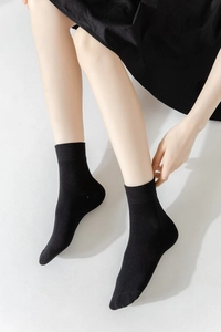 Detail of black mid-calf socks with ribbed cuffs and smooth combed cotton texture