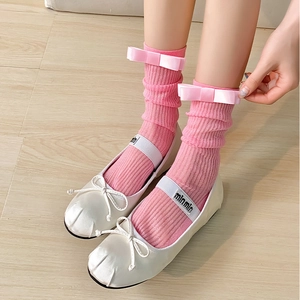 Détail du nœud rose sur chaussettes côtelées avec ballerines Mary Jane en soie blanche
