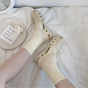 Cream woven fisherman sandals with ribbed cotton socks in a minimalist cozy home setting