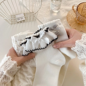 Detail of white Lolita socks featuring ruffled lace edges and delicate satin bows
