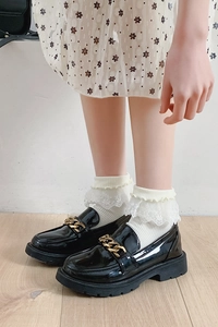 Détail de chaussettes en dentelle blanche avec perles et nœud et mocassins vernis