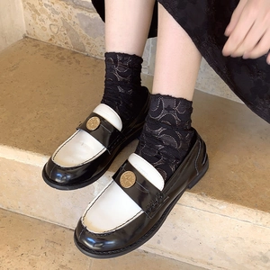 Detail of black and white leather coin loafers with lace socks on stone steps