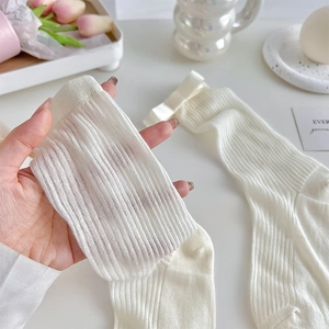 Gros plan de chaussettes en tricot blanc avec nœuds en satin et texture douce