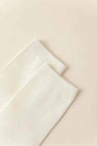 Gros plan détaillé des poignets côtelés sur des chaussettes tabi en coton écru