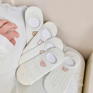 Detailed view of five white boat socks with cute cartoon embroidery and mesh texture