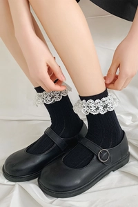 Détail de chaussettes mi-hautes noires en tricot avec bordure en dentelle blanche
