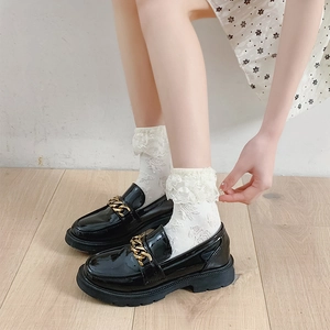 Gros plan sur mocassins plateforme en cuir verni noir avec chaîne dorée et dentelle