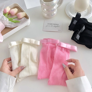 Détail de chaussettes en tricot avec nœuds satin, en blanc, rose et noir