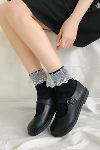 Détail de chaussures Mary Jane noires avec boucle en métal et chaussettes à bordure dentelle